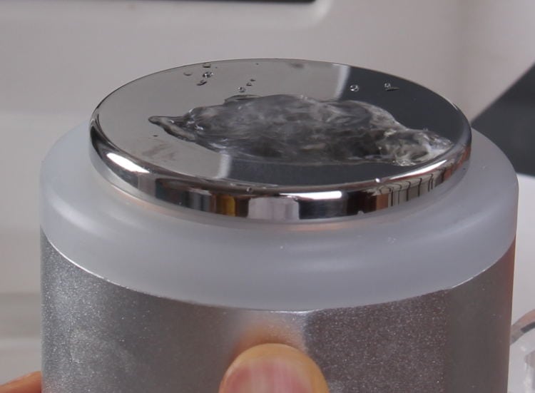 En person holder et sølv kaffekrus fyldt med vand og fremviser den professionelle bedste OSANO Ultrasonic Innovation Cool Cavitation Liposuction Machine.