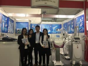 A group of people standing in front of a booth showcasing beauty equipment at the Cosmoprof Bologna trade show, including the brand OSANO.