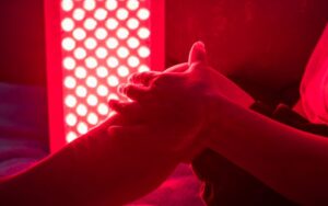 Hand massage therapy in a warm red light environment promoting relaxation and comfort for stress relief and wellness.