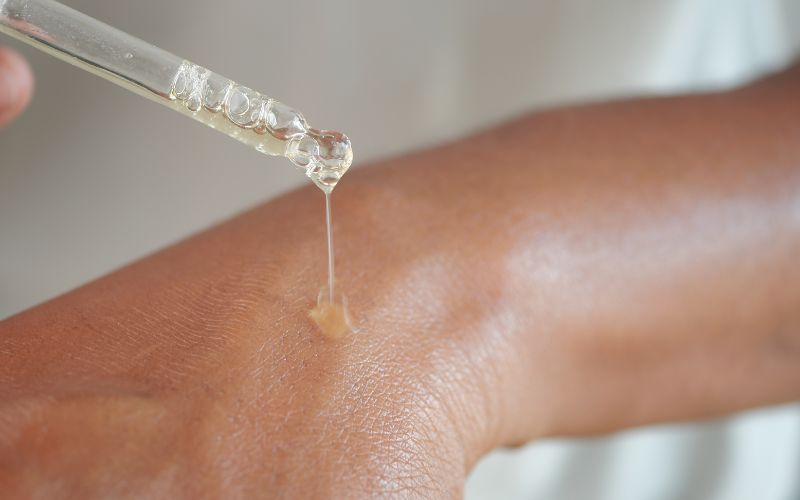 Clear CBD oil dropper applying oil onto skin for pain relief or skin health—promoting relaxation and comfort.