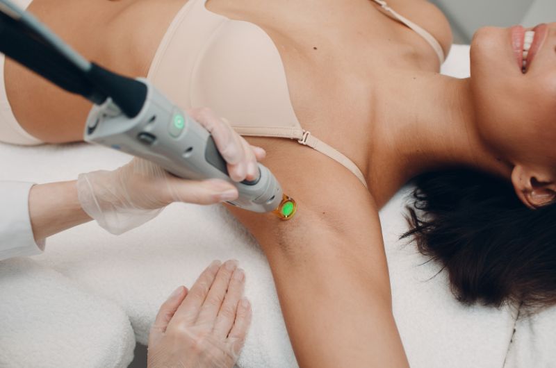 ALT: Woman receiving laser skin treatment on her armpit in a professional clinic setting for hair removal or skin enhancement.