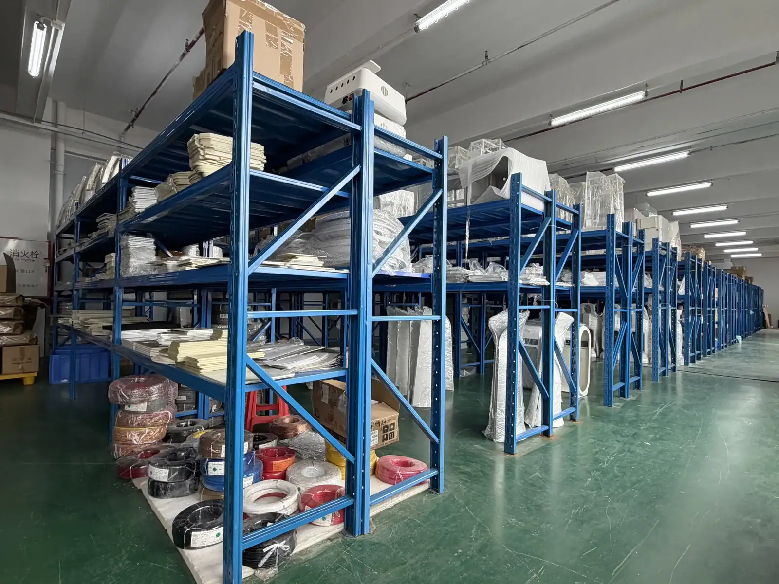 Industrial storage shelves filled with various equipment, tools, and supplies in a warehouse setting.