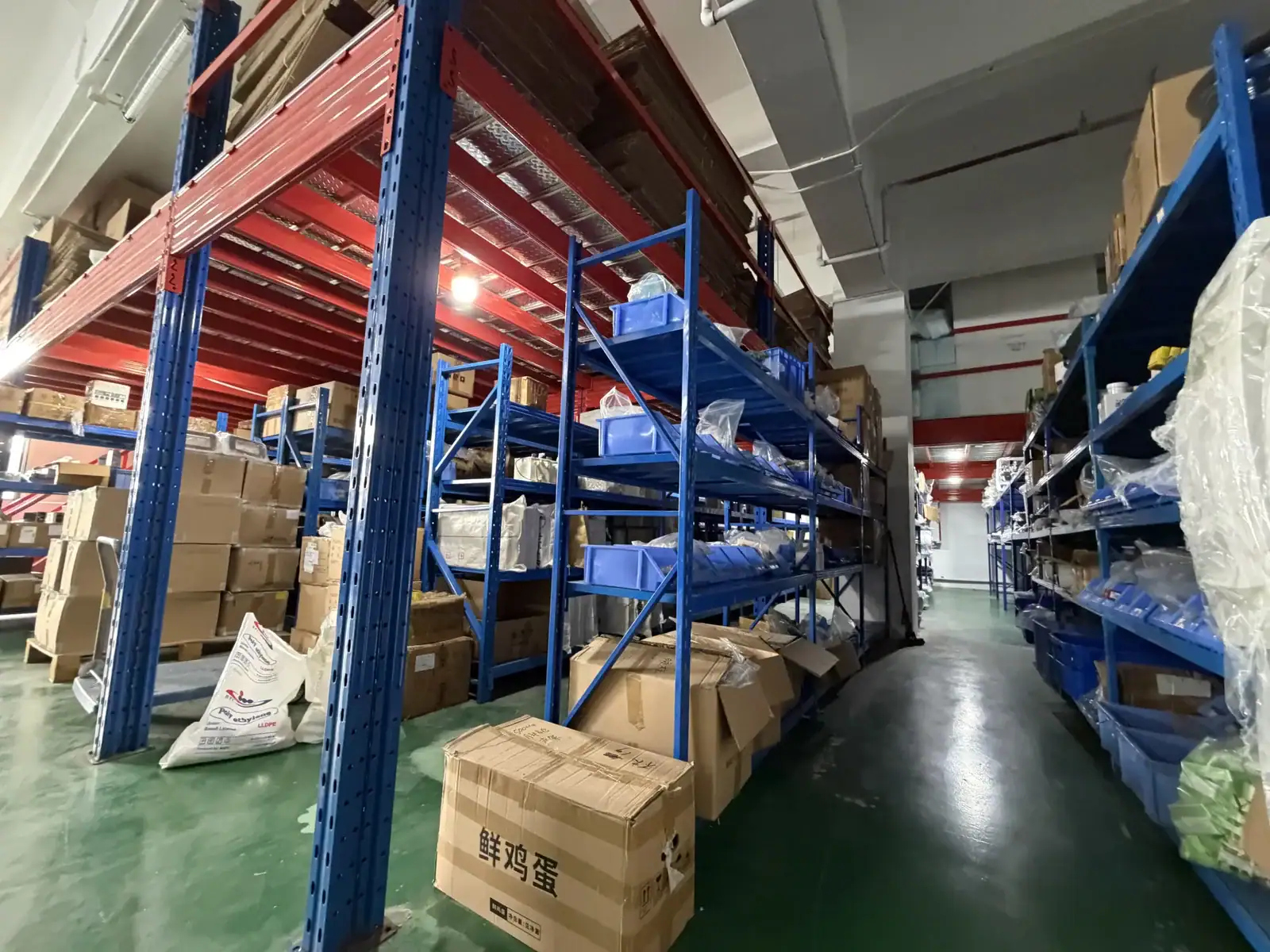 Industrial warehouse with blue metal shelving units filled with cardboard boxes and packages, organized for inventory management.